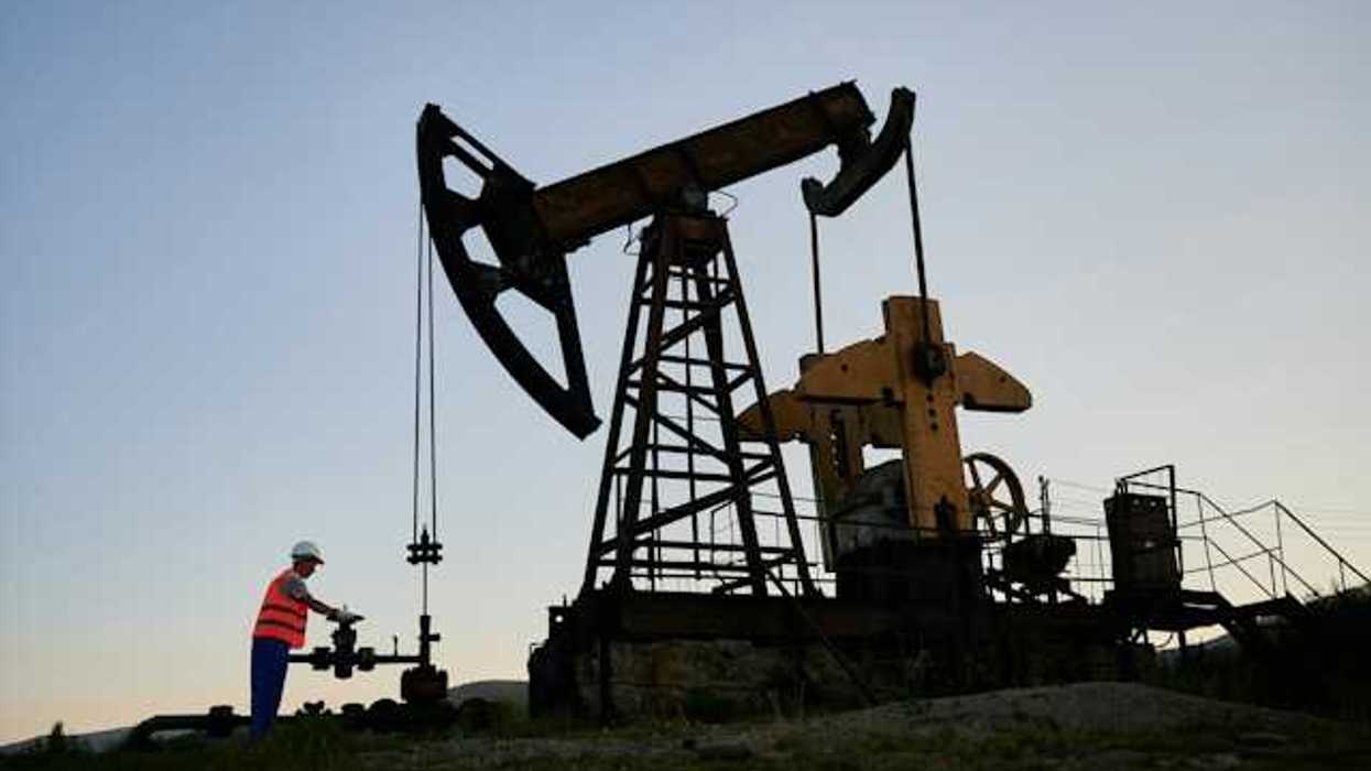 An oil pump jack silhouetted against a sky at dusk