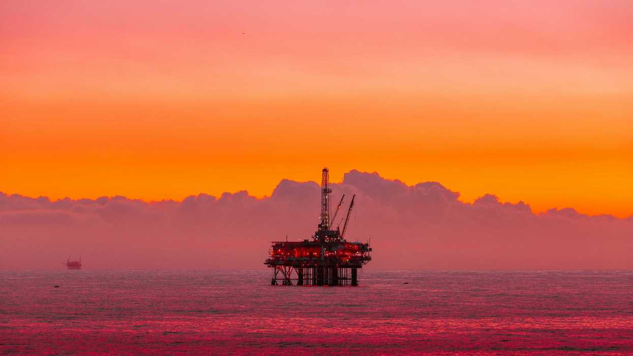 an oil rig in the middle of the ocean at sunset.