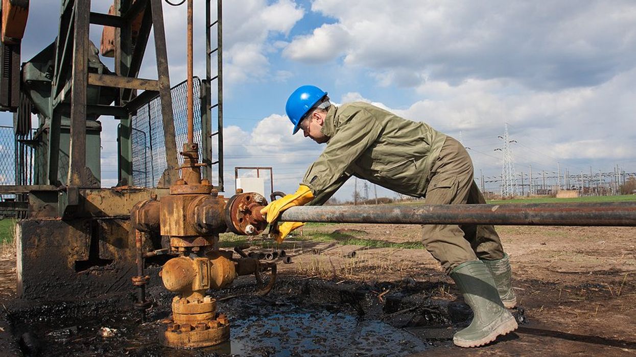 An oil worker using equipment to stop a leak.