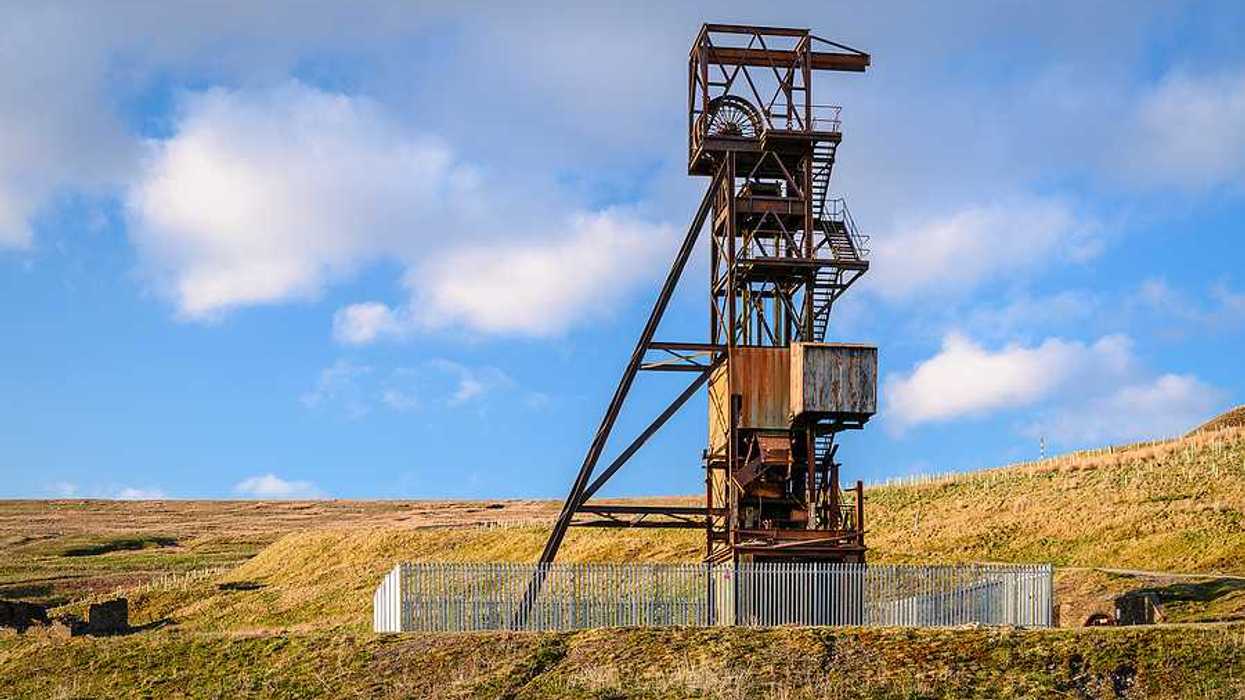An old mine tower surrounded by a green field
