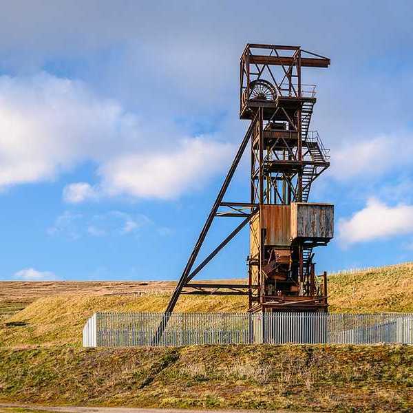 An old mine tower surrounded by a green field