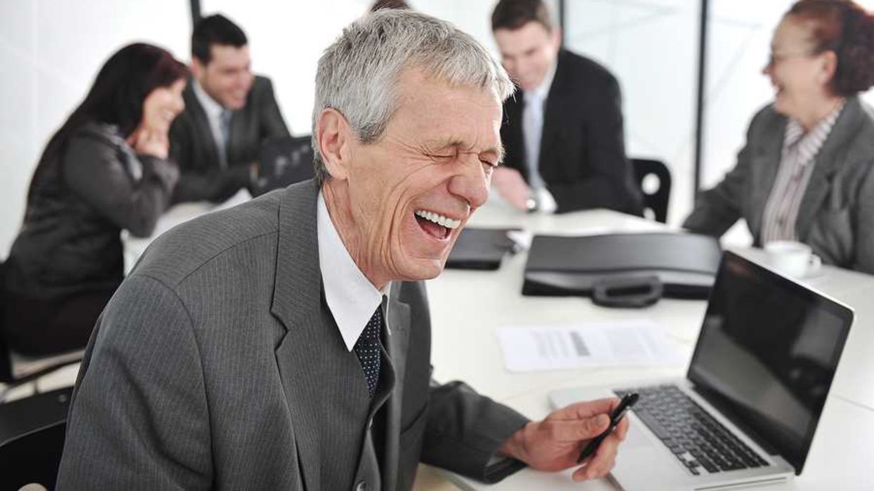 An older businessman in a meeting laughing