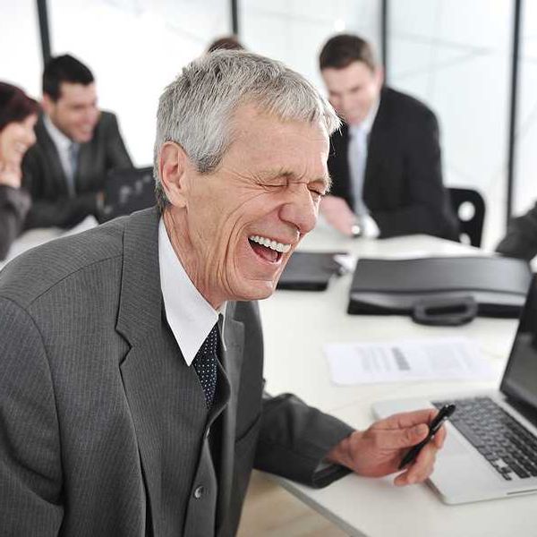 An older businessman in a meeting laughing