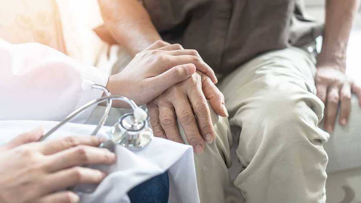 An older gentleman sitting with a doctor's hand on his