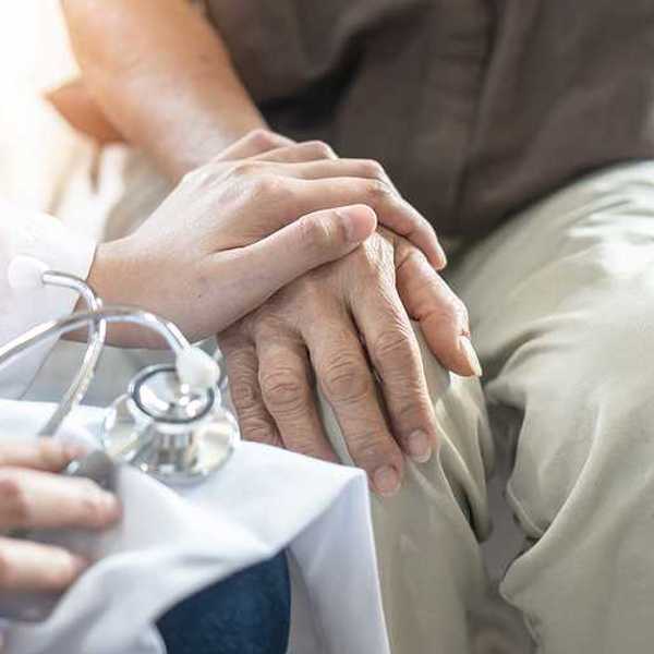 An older gentleman sitting with a doctor's hand on his