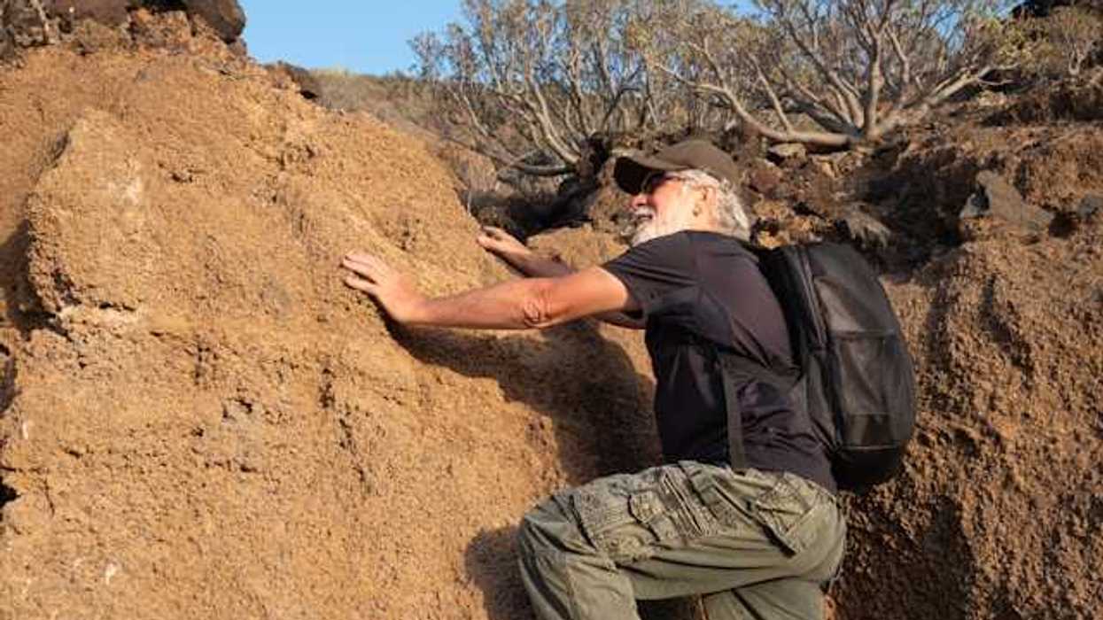 An older man climbing onto a dry rock