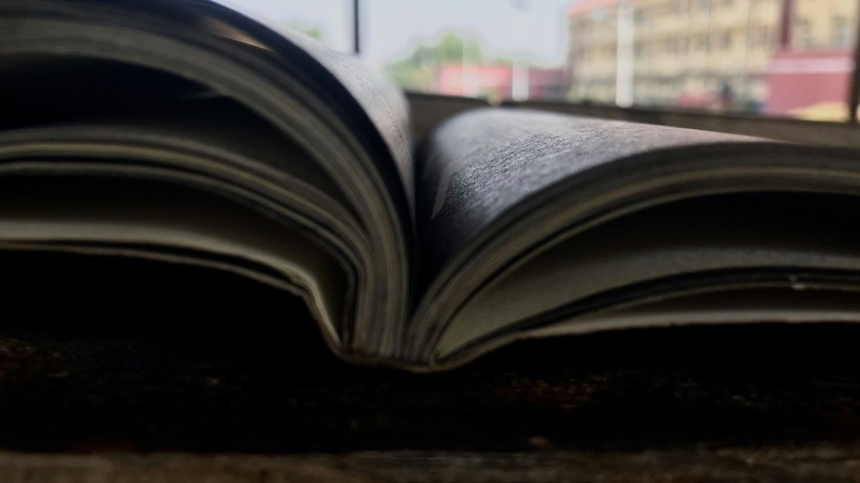 an open book sitting on top of a table with a window in the background.