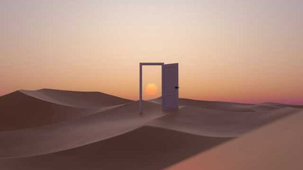 An open door in the middle of a desert with a sunset behind