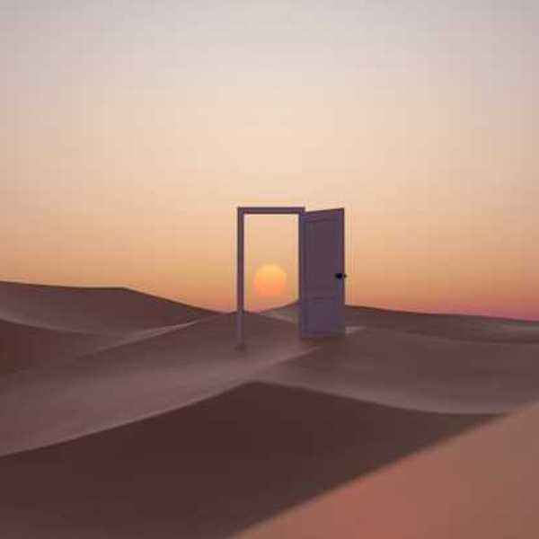 An open door in the middle of a desert with a sunset behind