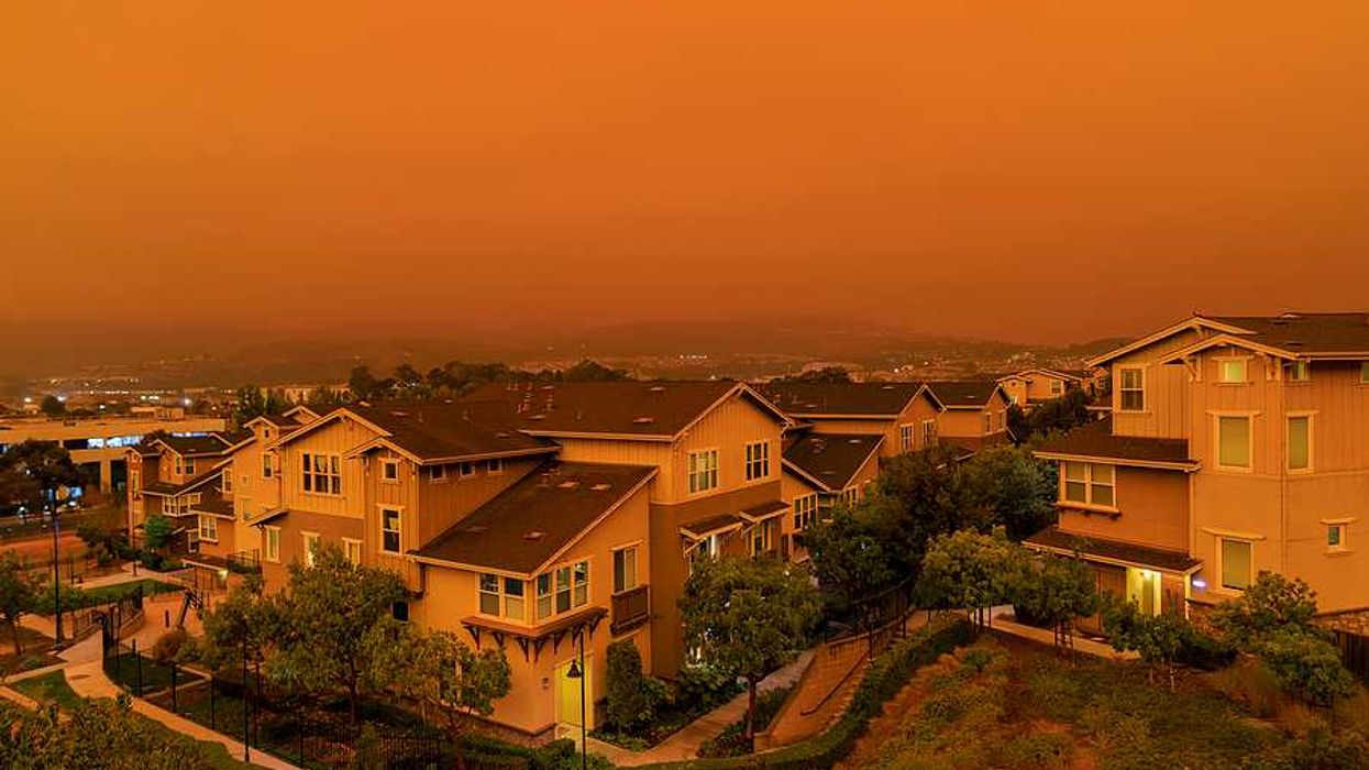 An orange-tinged sky and houses during a wildfire