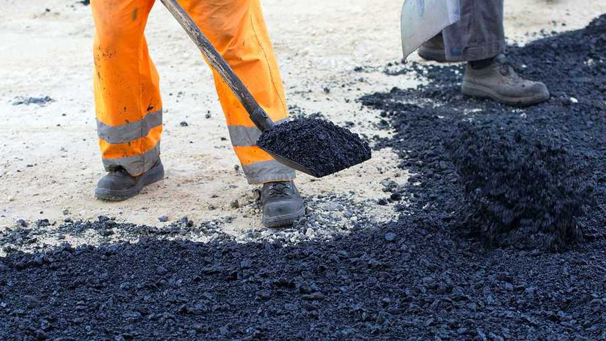 An outdoor worker laying asphalt