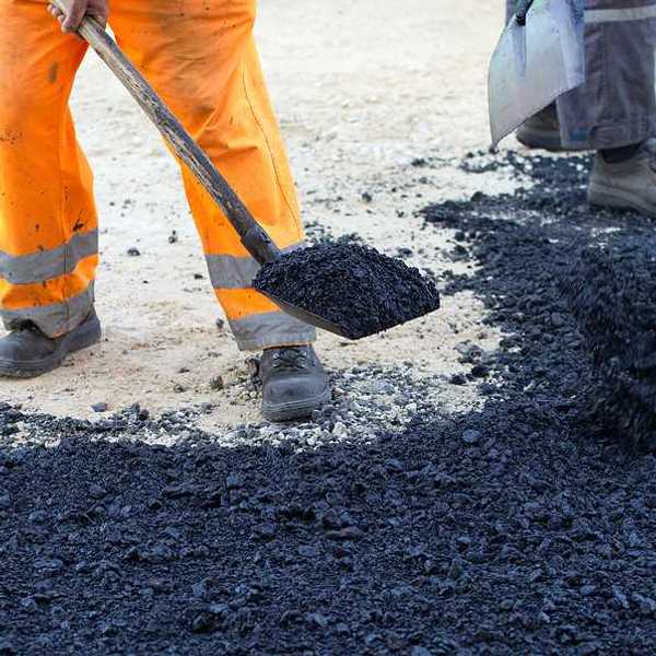 An outdoor worker laying asphalt