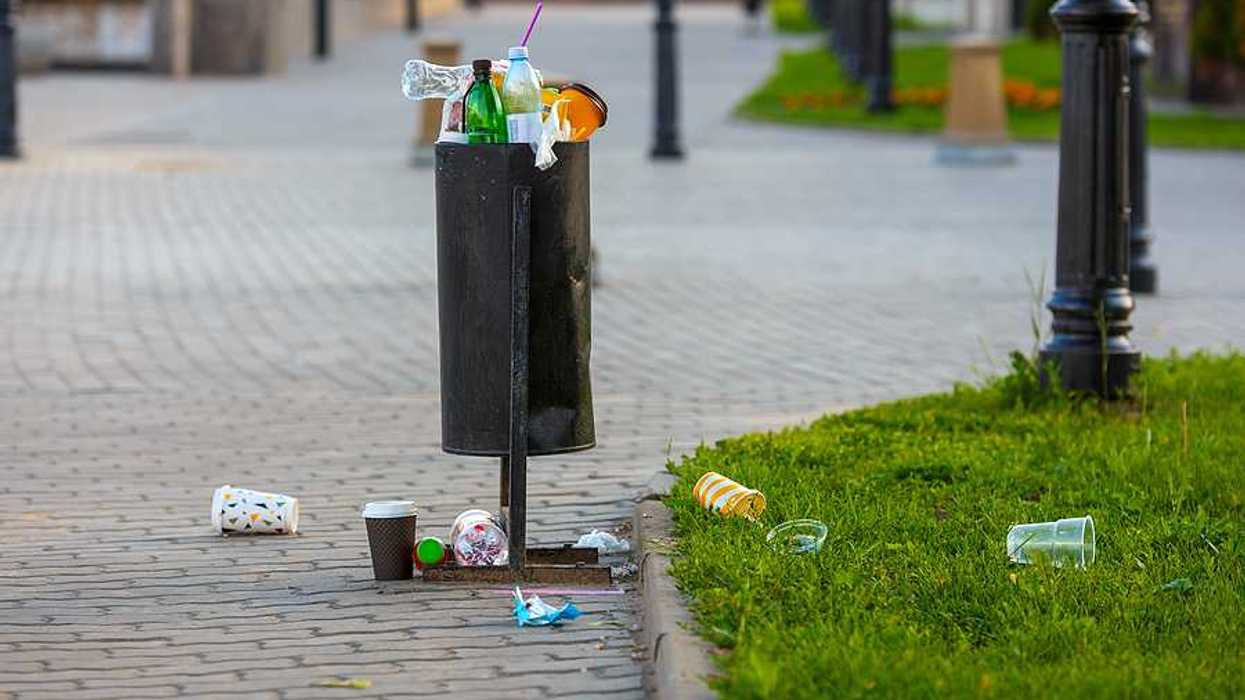 An overflowing trash can in a park