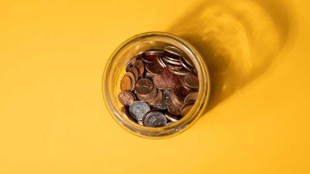 An overhead view of a jar of coins on a yellow background