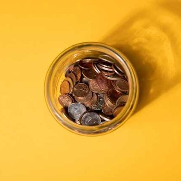 An overhead view of a jar of coins on a yellow background
