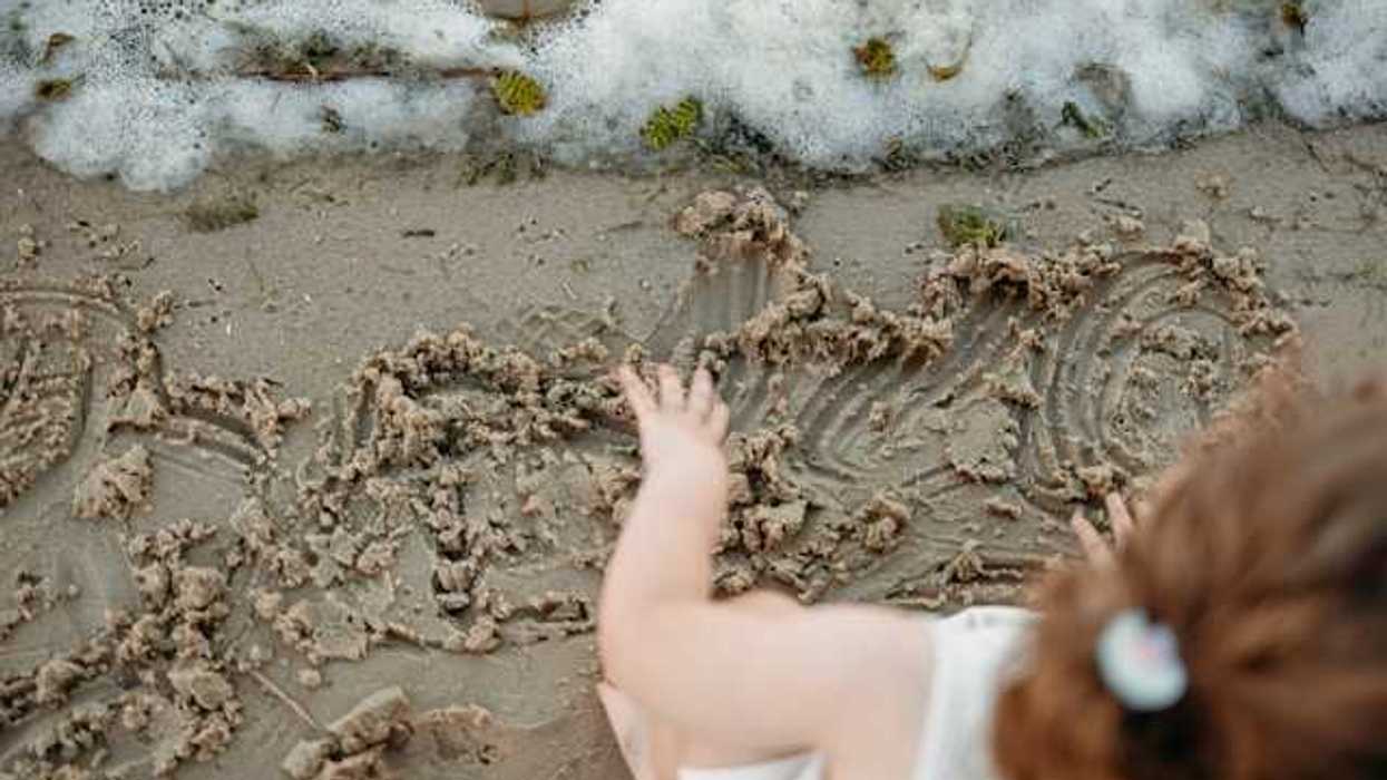 An overhead view of a small child playing in the sand on a beach