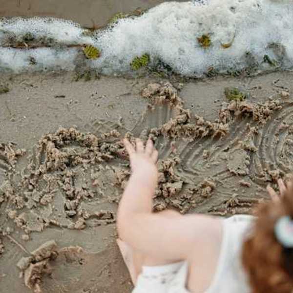 An overhead view of a small child playing in the sand on a beach