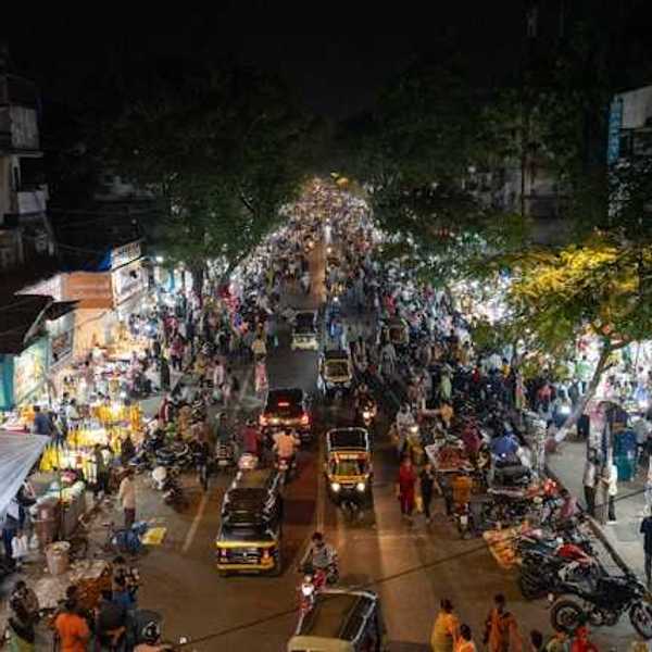 An overhead view of a street in Mumbai, India at night filled with cars, people, and shop entrances