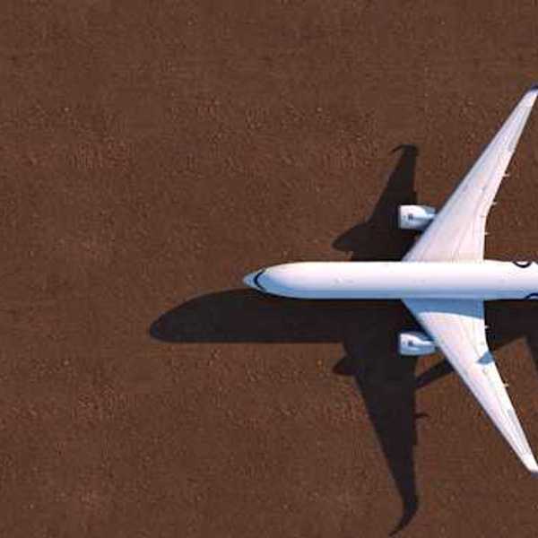 An overhead view of a white airplane on a brown tarmac