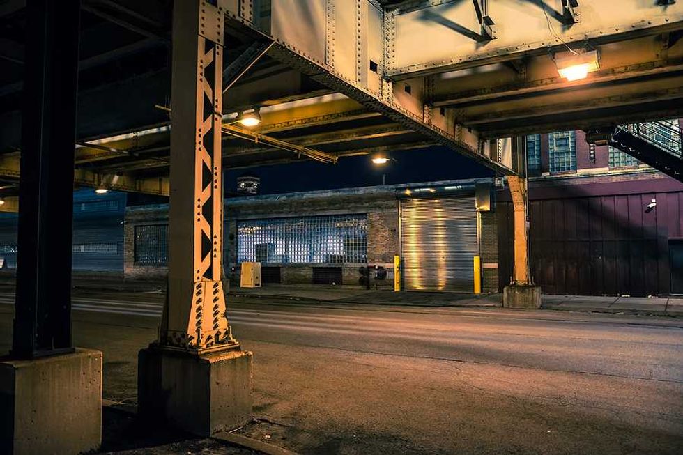 An urban street scene under an elevated train track