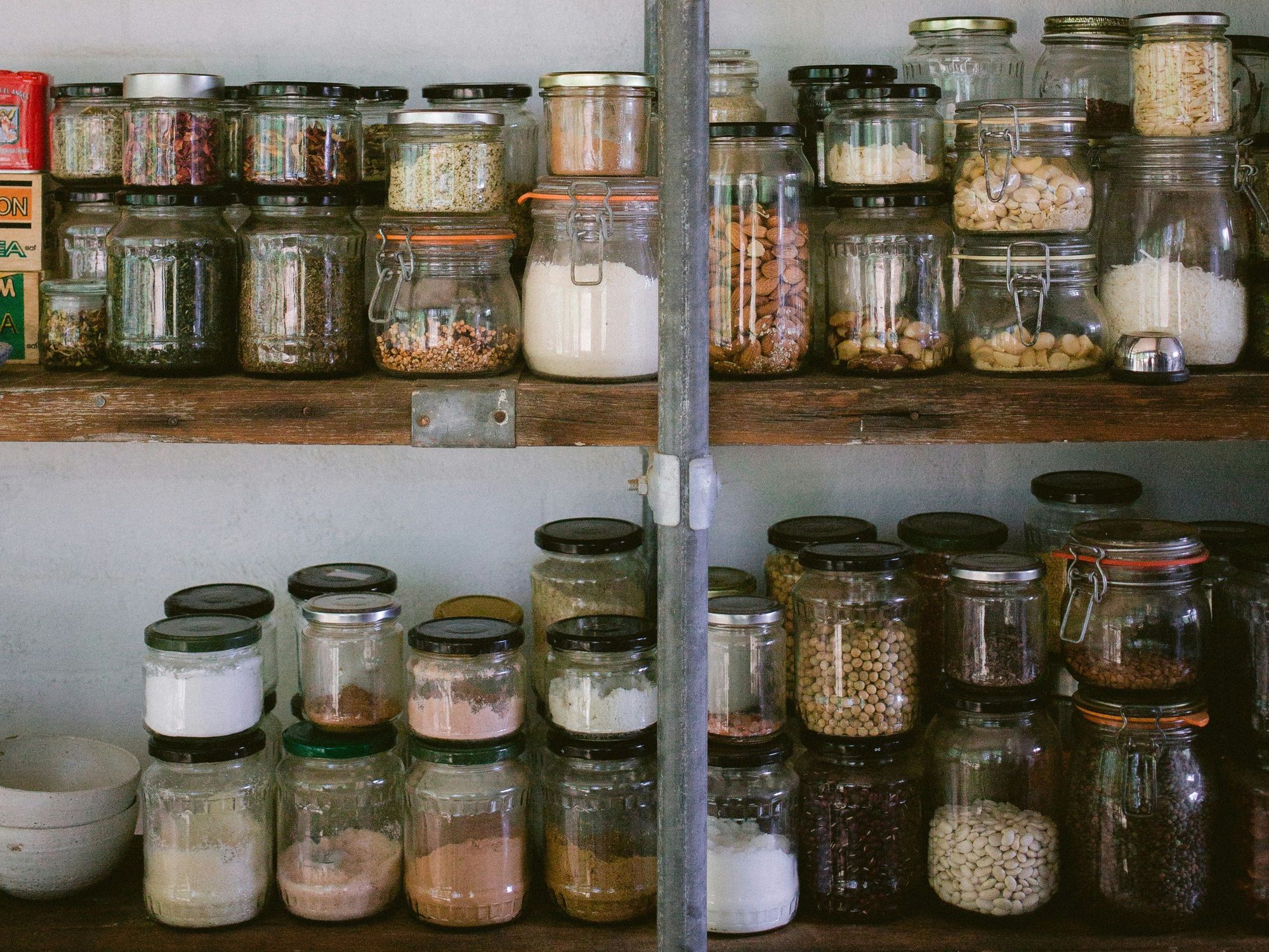 assorted glass jars on white wooden shelf.