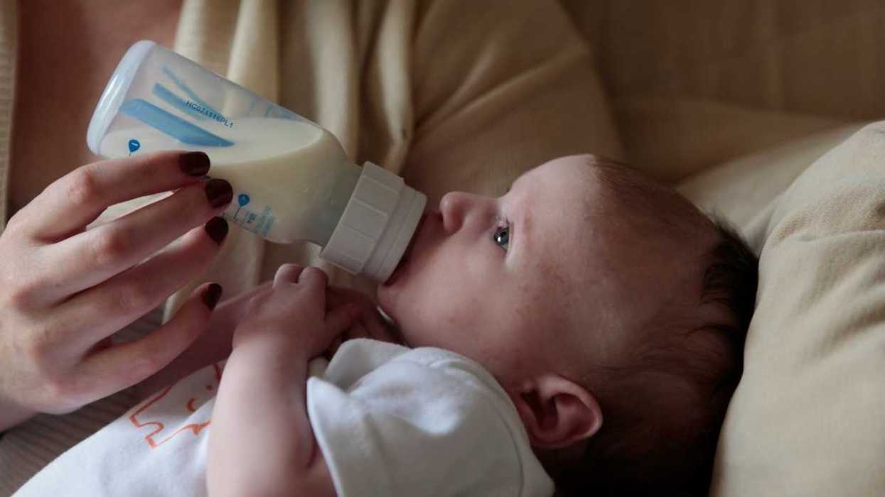 Baby being bottle-fed from plastic bottle