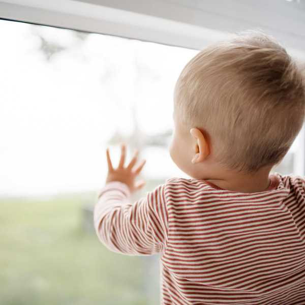 Baby in red and white striped shirt looking out the window.