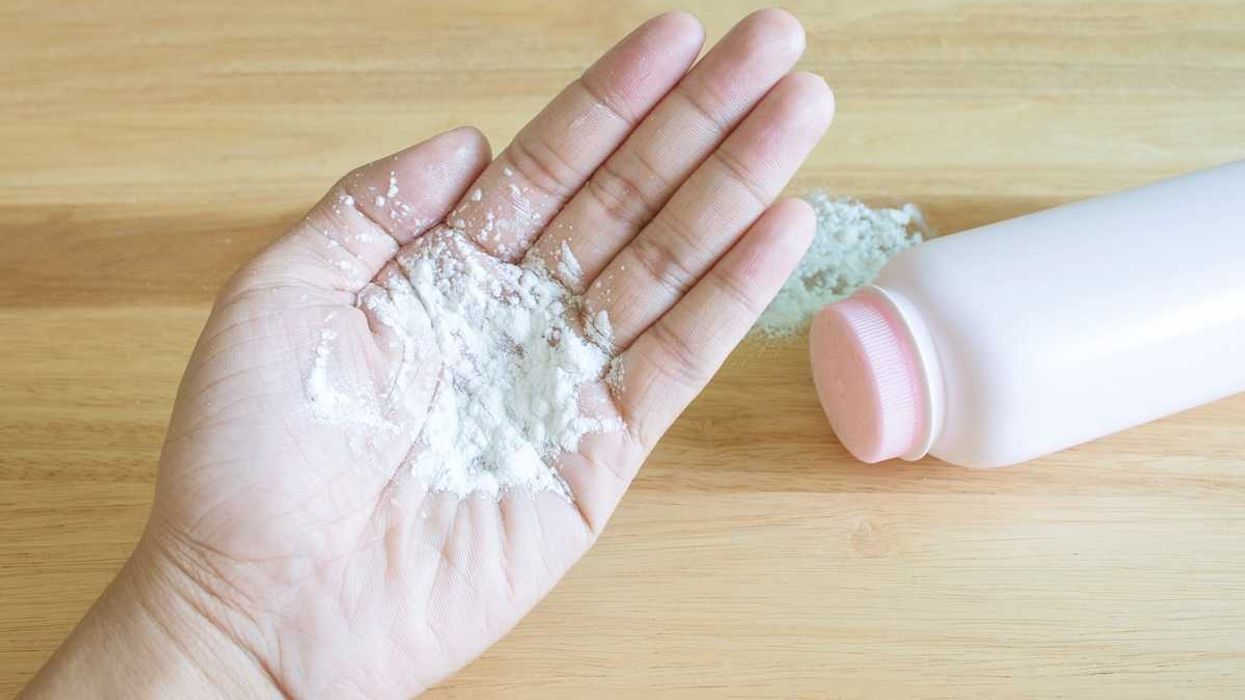 Baby talcum powder on hand wooden background
