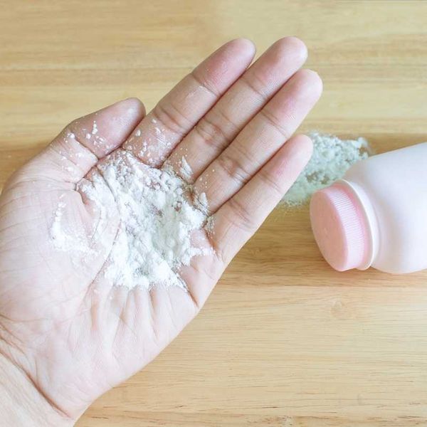 Baby talcum powder on hand wooden background
