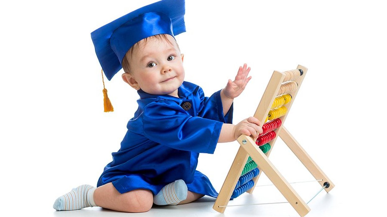 Baby wearing blue graduation gown and cap in front of an abacus.