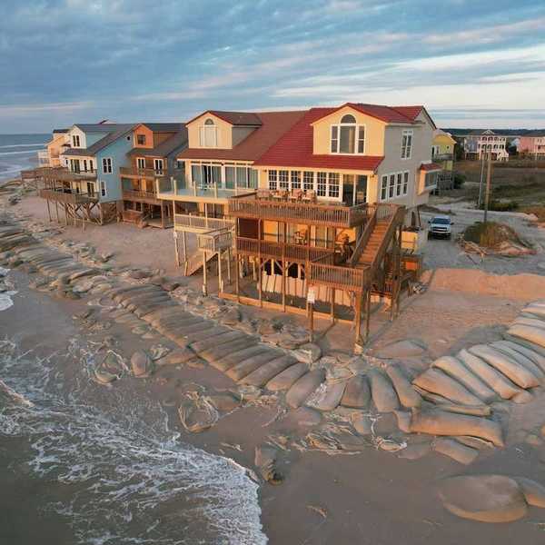 Beach homes, partially protected by sand bags, at the edge of North Topsail Island in North Carolina coast.