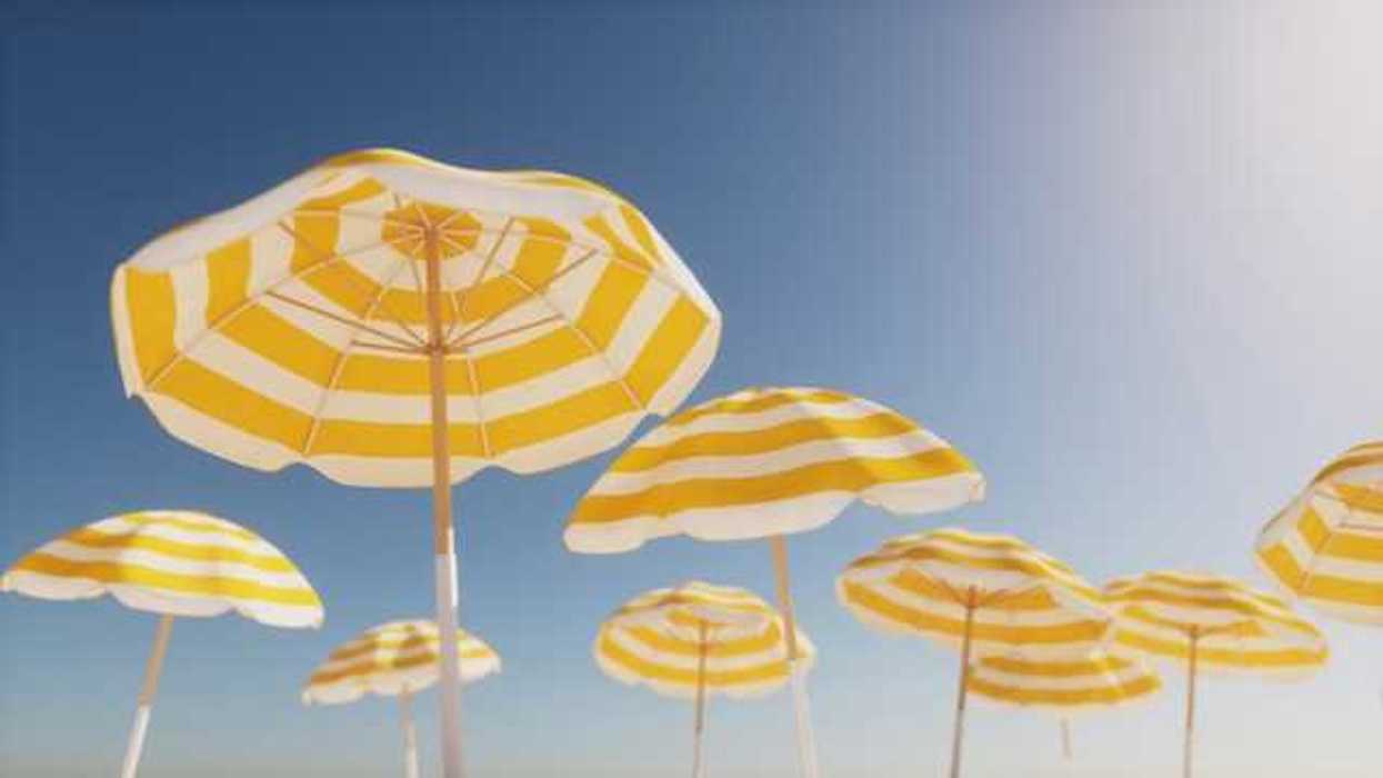 Beach umbrellas with yellow and white stripes against a blue sky