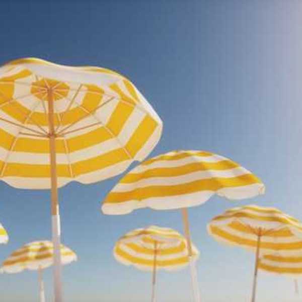 Beach umbrellas with yellow and white stripes against a blue sky