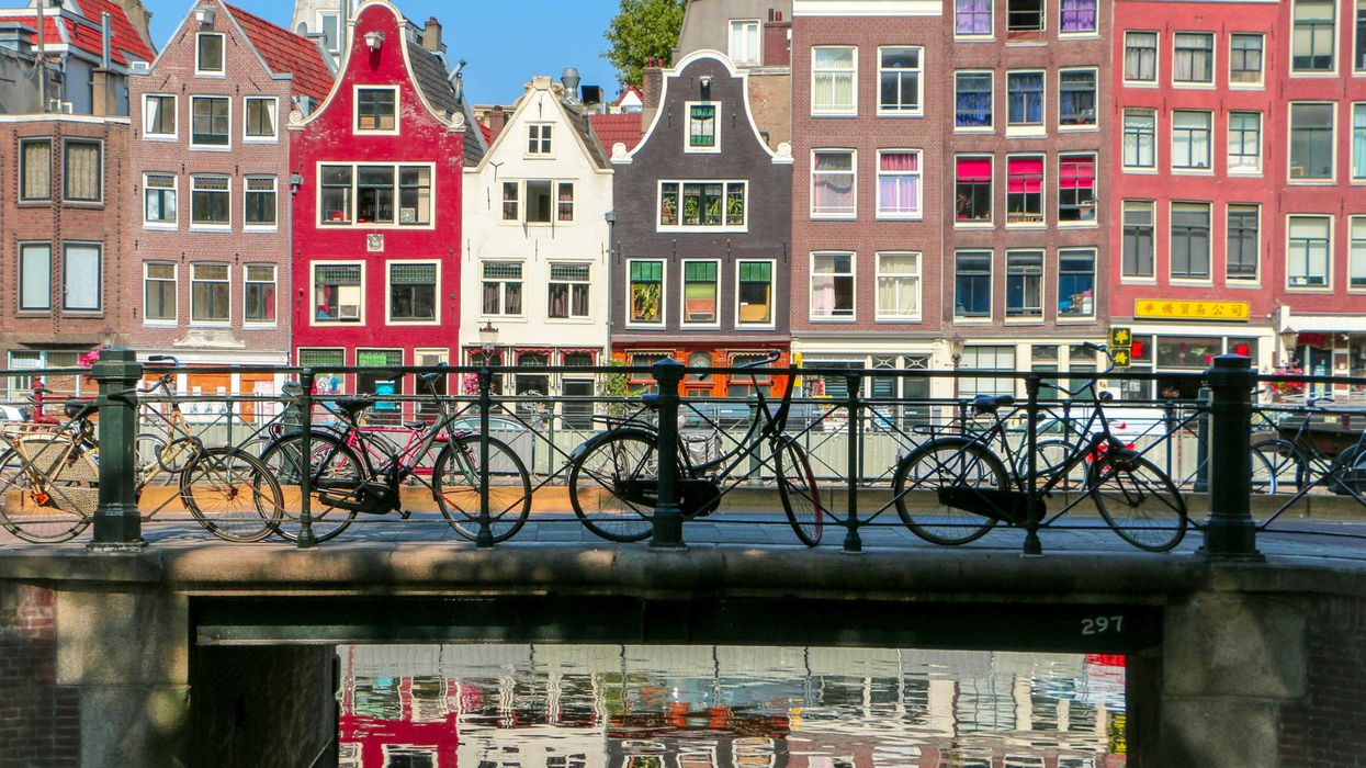 Bicycles leaning against a railing on a bridge over a canal in Amsterdam