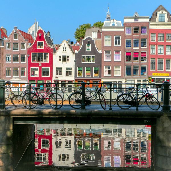 Bicycles leaning against a railing on a bridge over a canal in Amsterdam