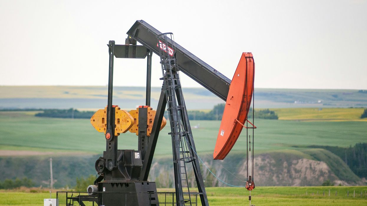 black and orange oil pump jack on green grass field during daytime