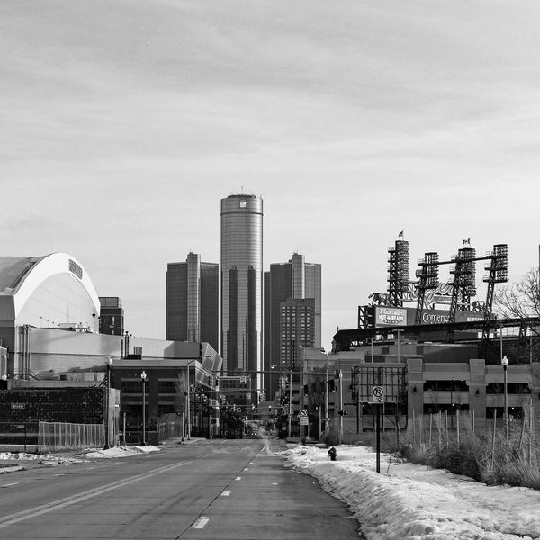 Black and white photo of a snowy street with city buildings in the background