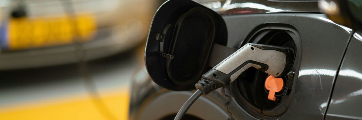 Black electric vehicle with charger attached.