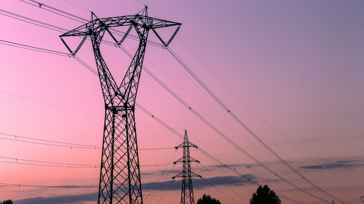 black electricity tower under a pink sky during sunset