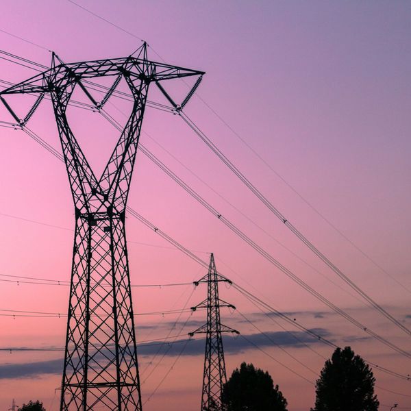 black electricity tower under a pink sky during sunset
