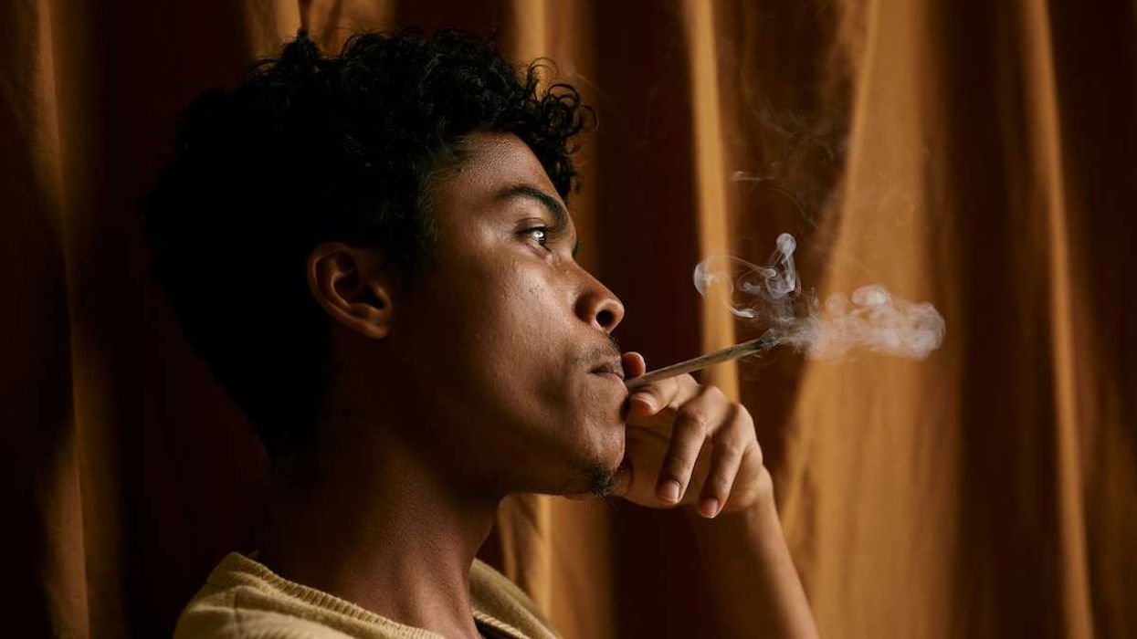 Black man smoking hand-rolled tobacco cigarette