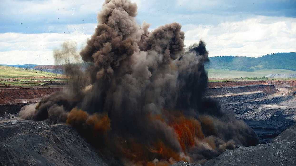 Blasting being carried out at an open pit coal mine. Explosion spewing smoke and debris to remove overburden.