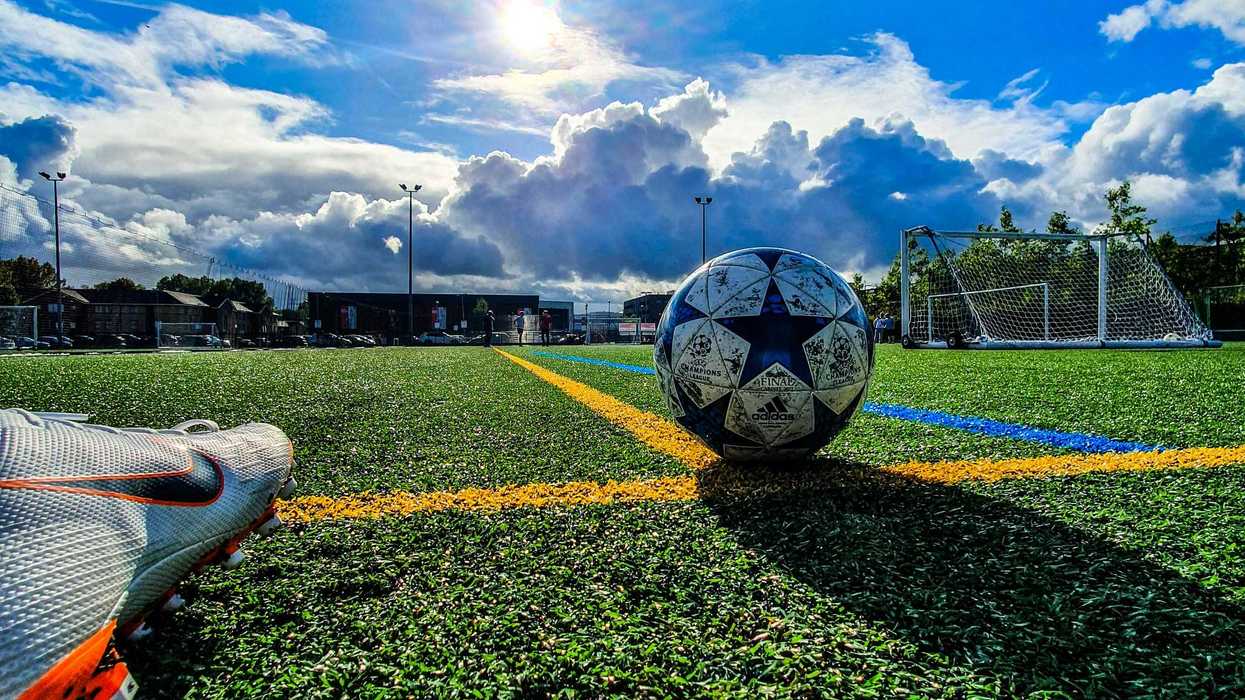 blue and grey soccer ball on green field under white and blue sky during daytime.
