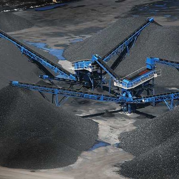 Blue cranes placing coal onto large piles