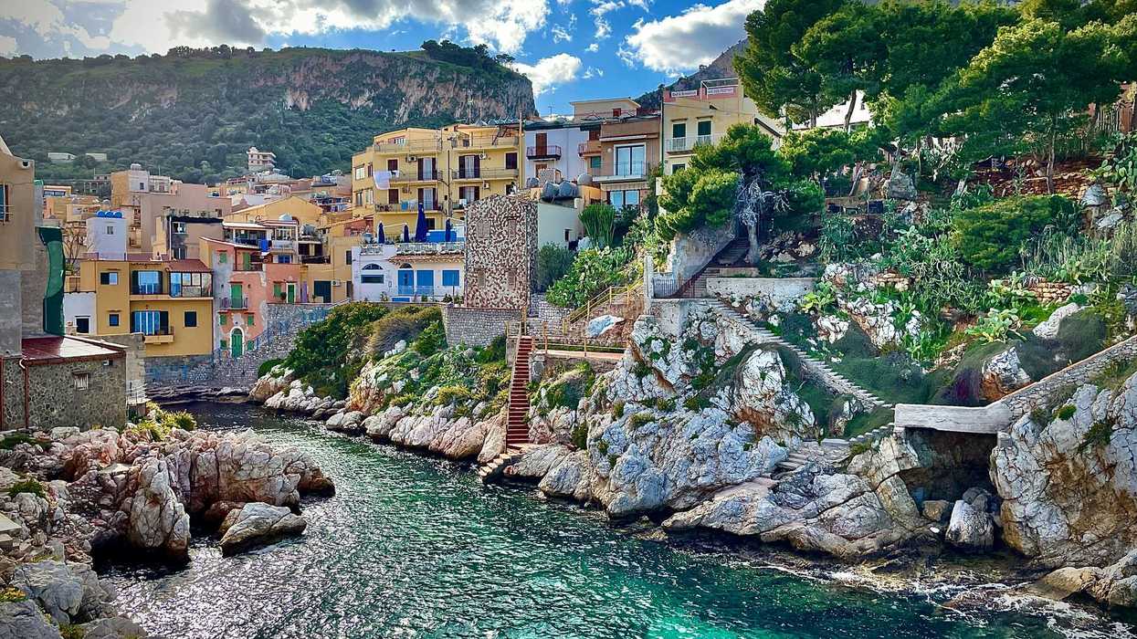 Blue-green sea water with a mediterranean village on the hills above the water
