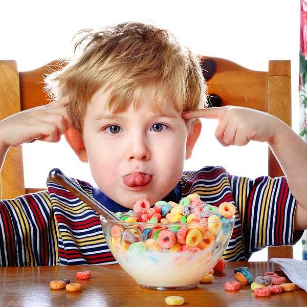 Boy eating multi-colored cereal  at a table