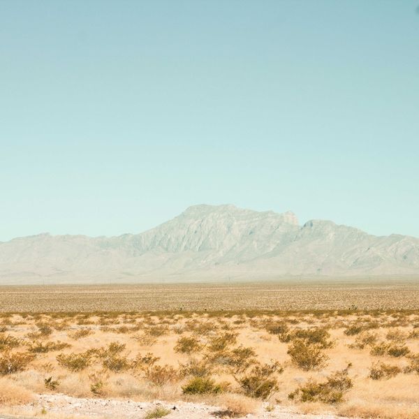 brown field near mountain under blue sky during daytime