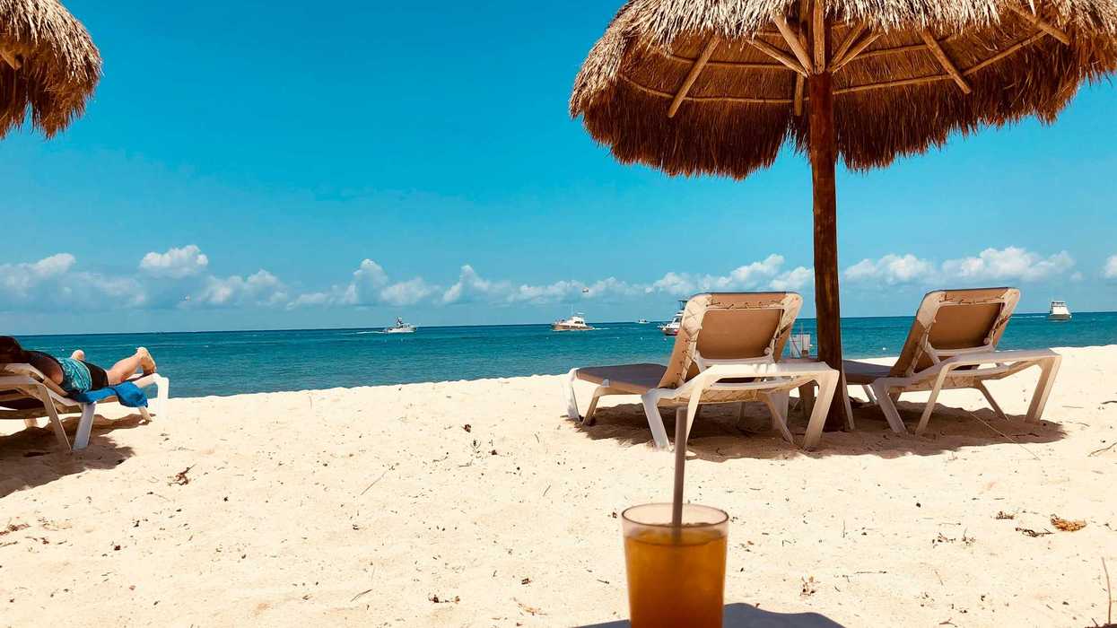 brown parasol and two beach chairs on beach sand