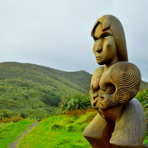 brown wooden human sculpture on green grass field
