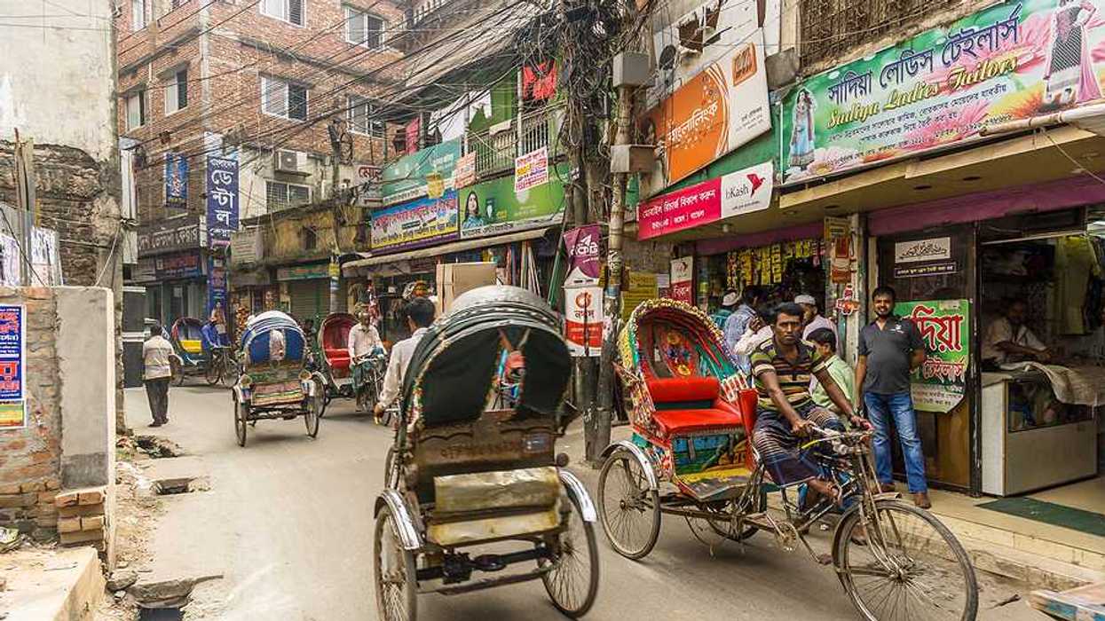 Busy street in Dhaka Bangladesh with brick buildings and rickshaws in the street